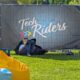 Mann liegt im Schatten eines großen Sichtschutzes mit TechRiders Logo