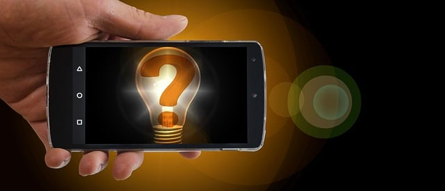 Smartphone in einer Hand. Auf dem Bildschirm ist eine Glühbirne in der ein Fragezeichen steht.